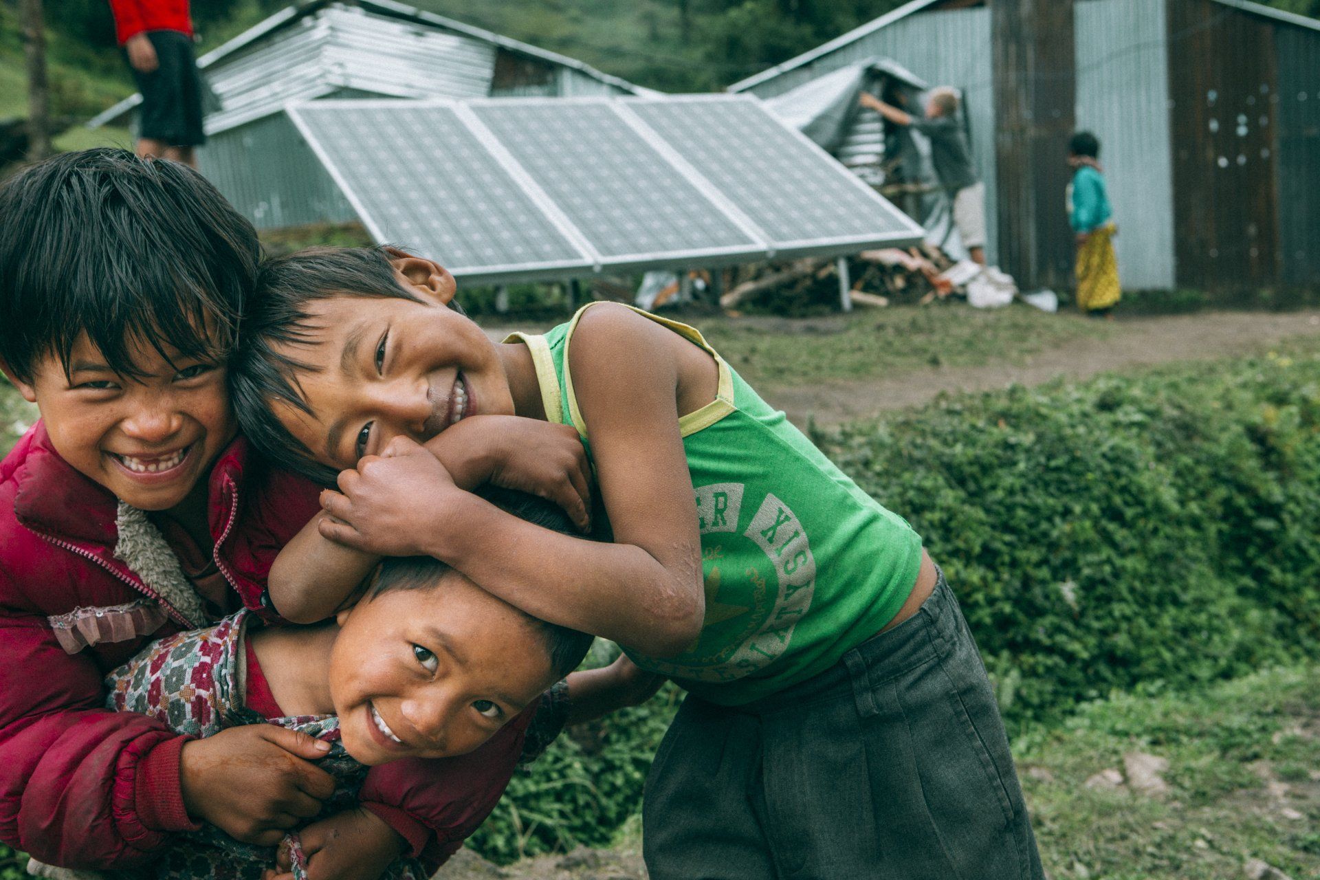 En grupp barn kramar varandra framför en solpanel.