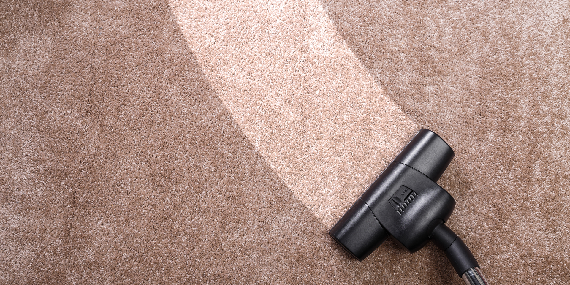 Vacuum cleaning a brown carpet.