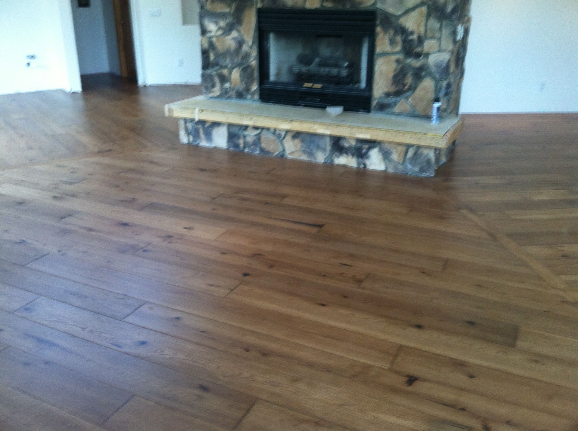 Empty room with hardwood floor and stone fireplace with black insert