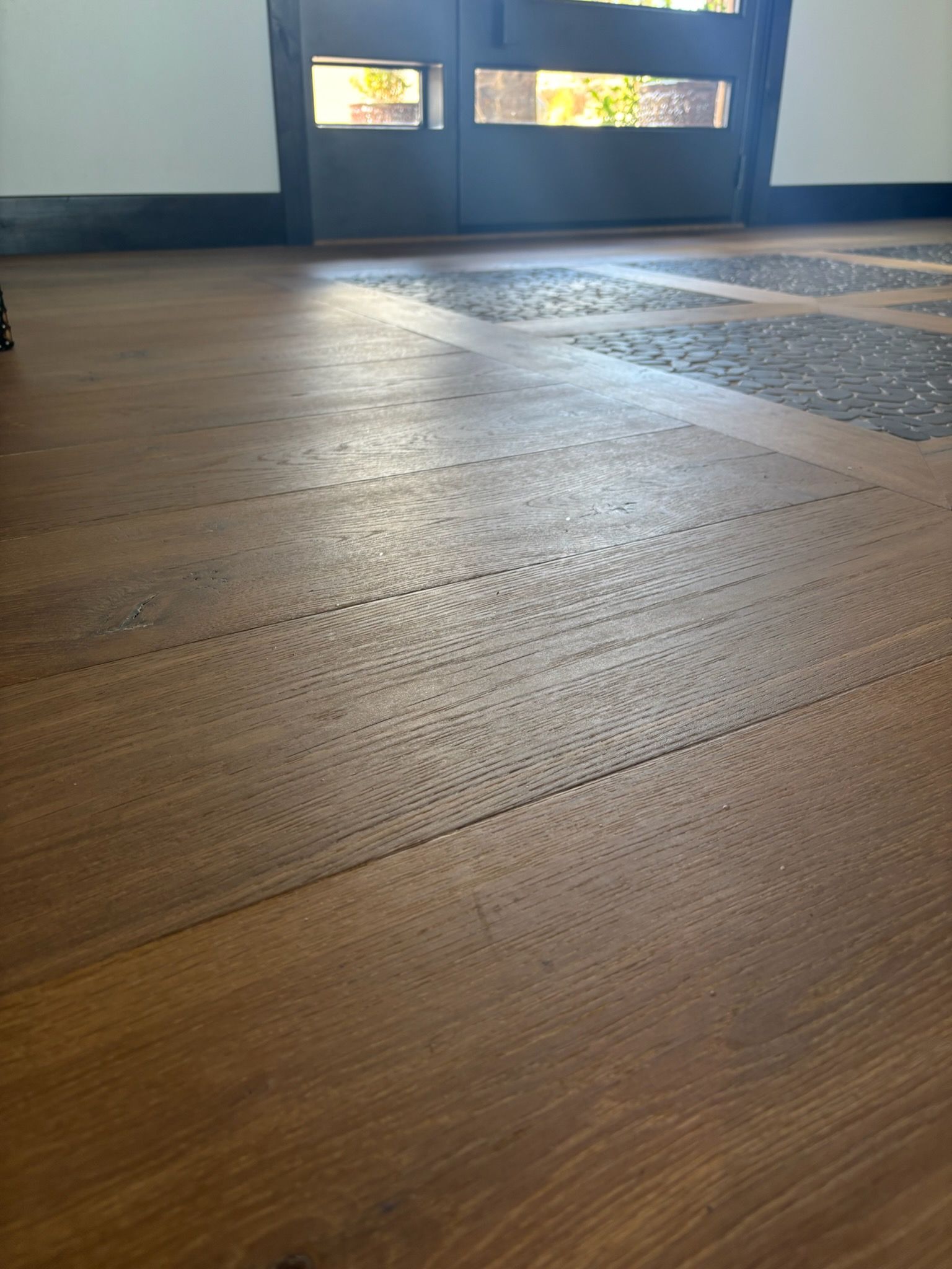 Wooden floorboards leading to a glass door with bright light shining through.
