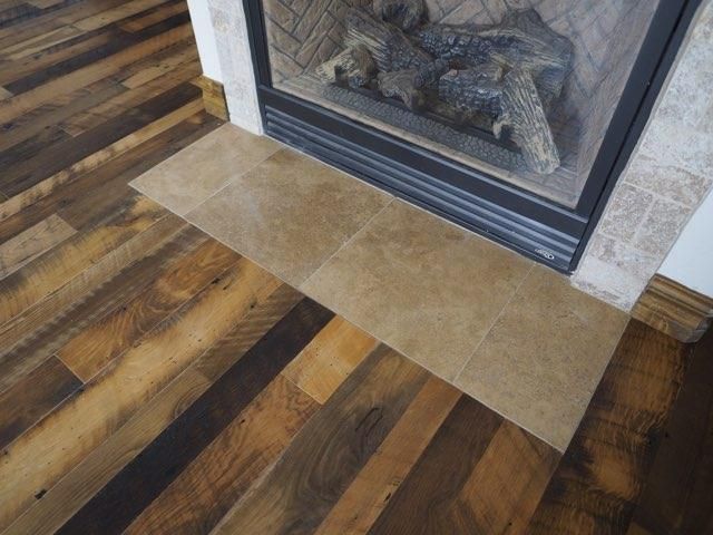 Wood-look floor with a tan tile hearth in front of a glass fireplace.