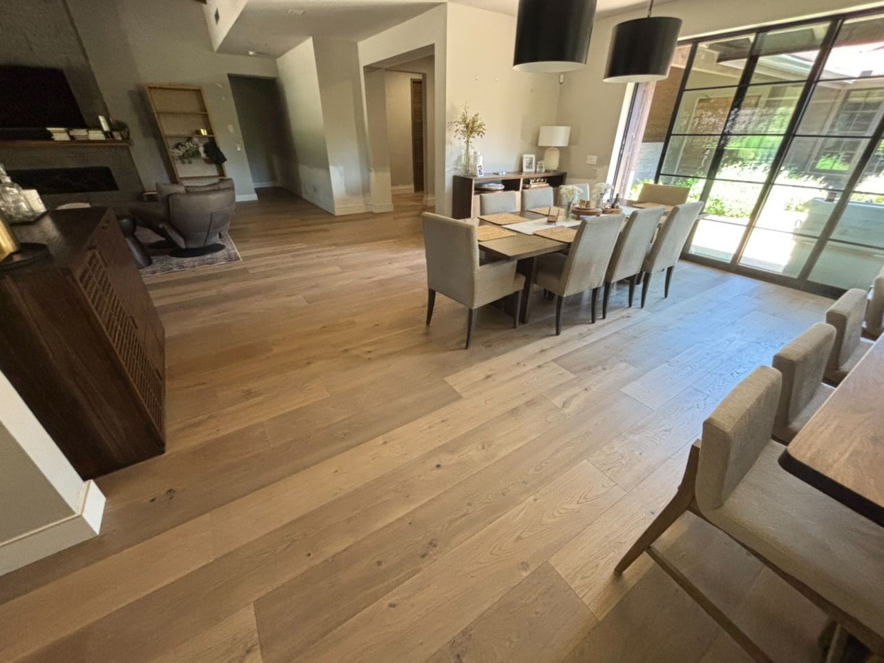 Bright open dining and living area with wood floors, table, chairs, sofa, and large sliding glass doors