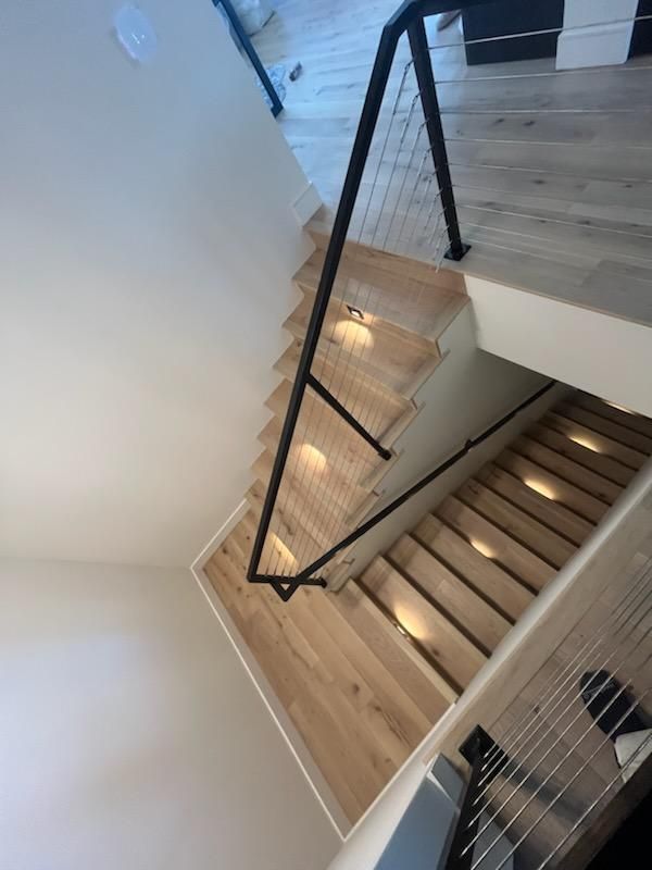 Stairwell with wooden steps, black metal railing, and skylight lighting in a modern interior