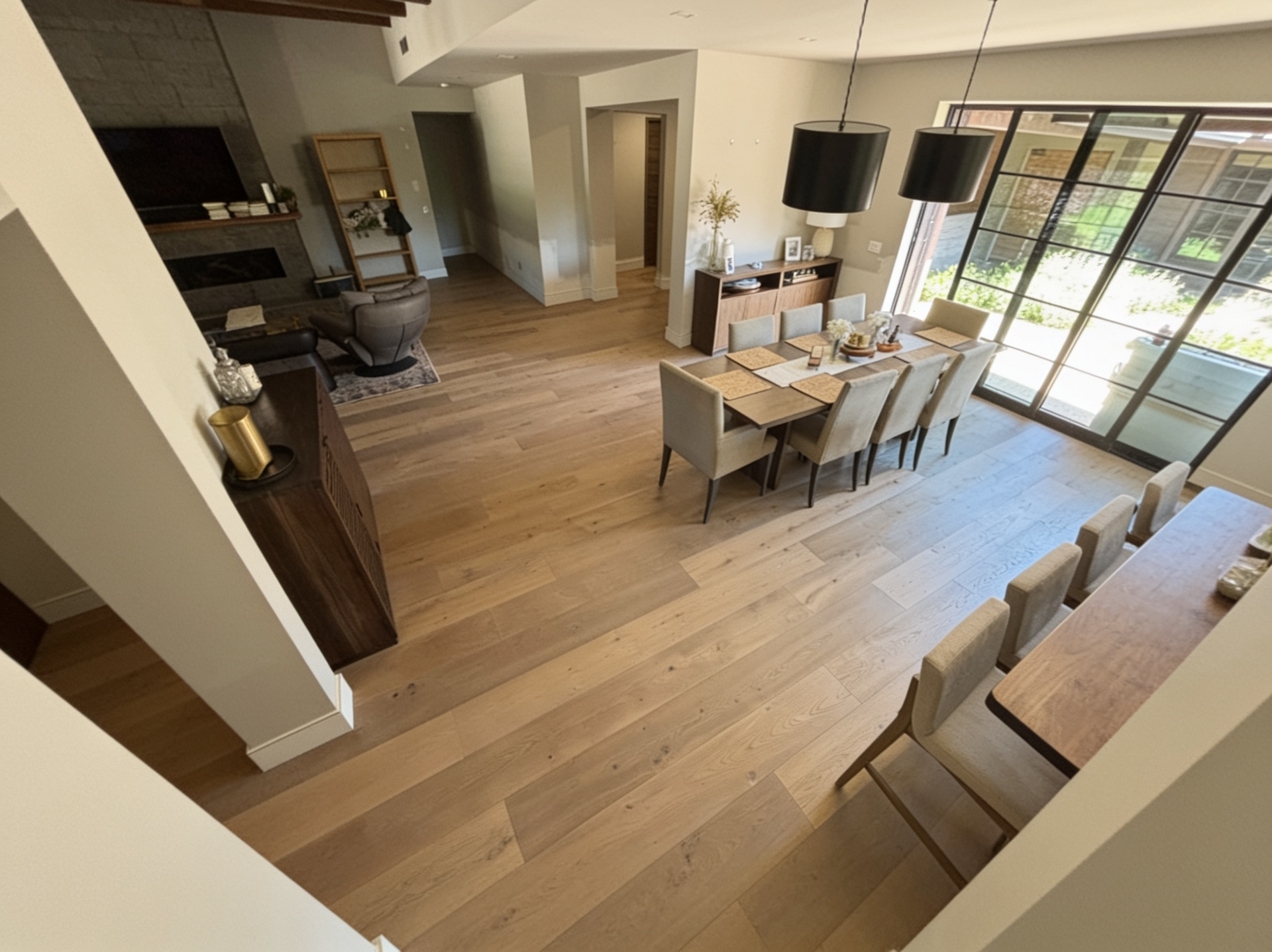 Open-plan dining and living area with wood floors, table set for four, and sliding glass doors to a patio