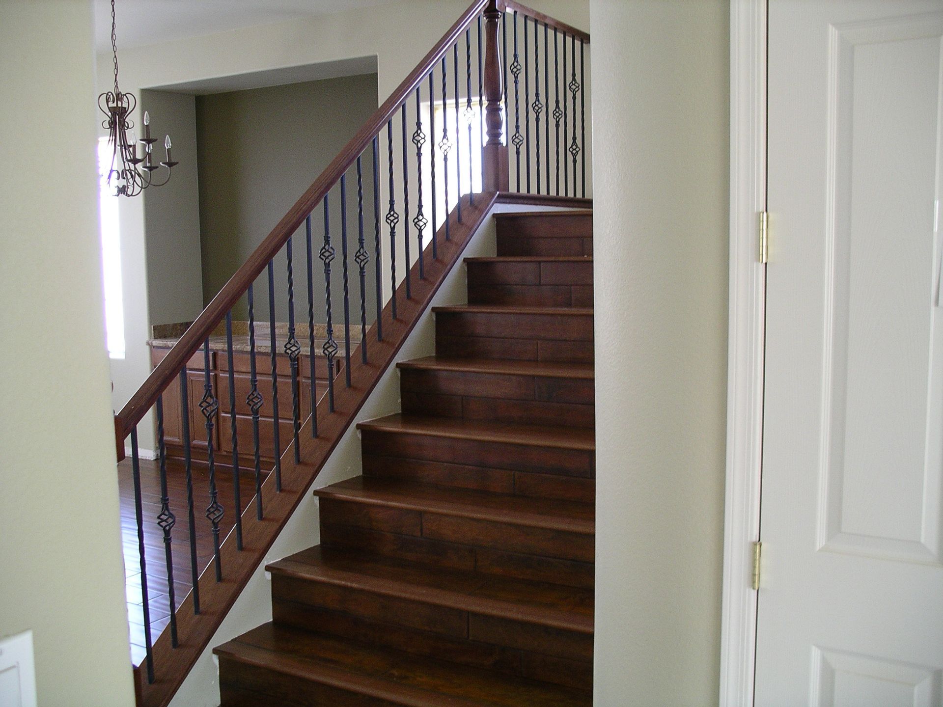Wooden staircase with dark railings in a home interior, leading to an upper floor.