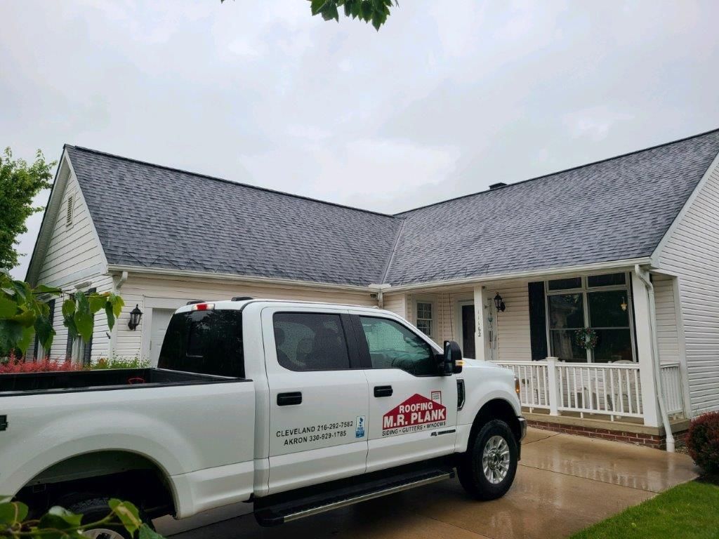 A white truck is parked in front of a white house.