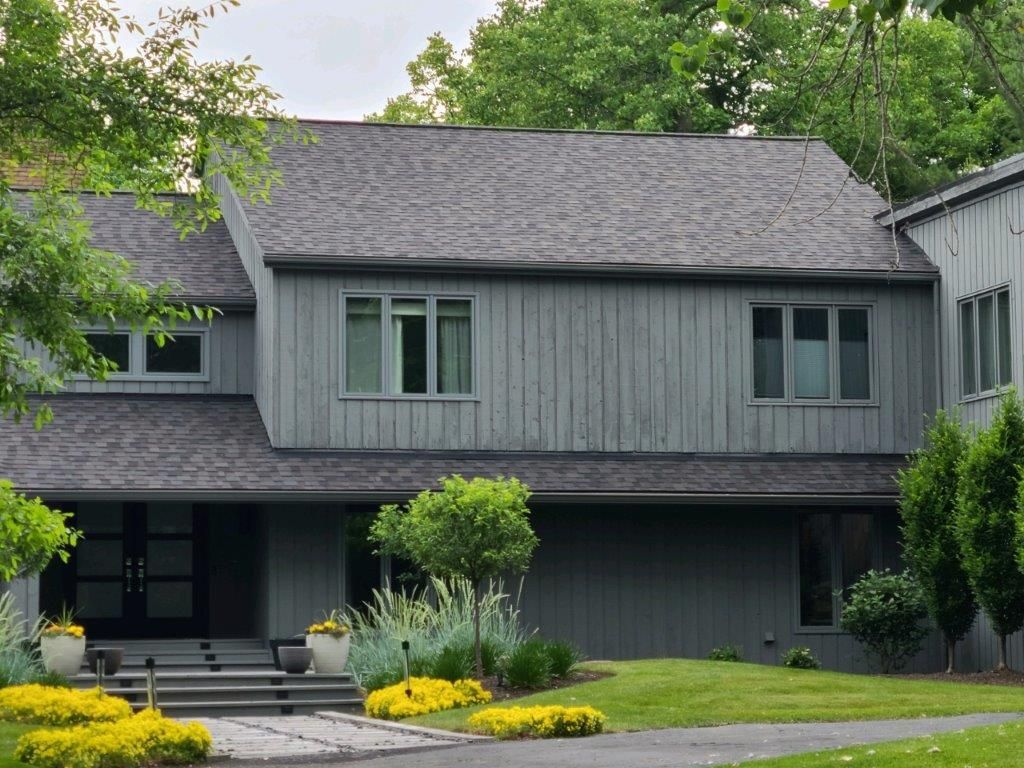 A large gray house with a gray roof and a lot of windows