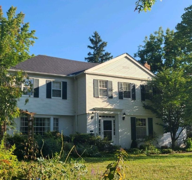 A white house with black shutters and a blue sky in the background