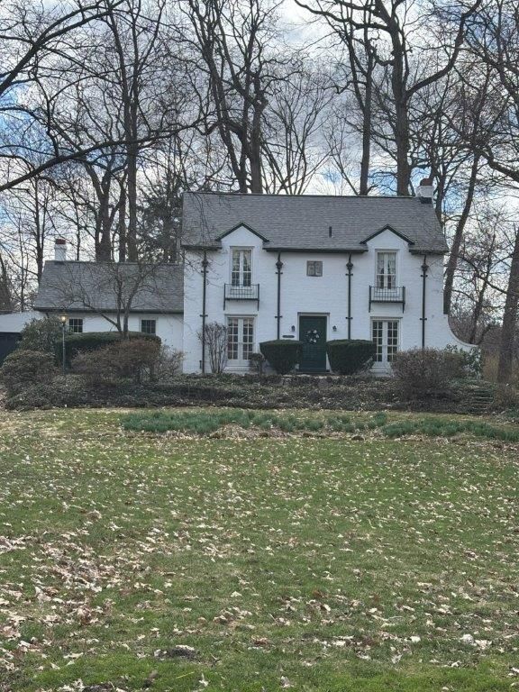 A large white house sits in the middle of a grassy field