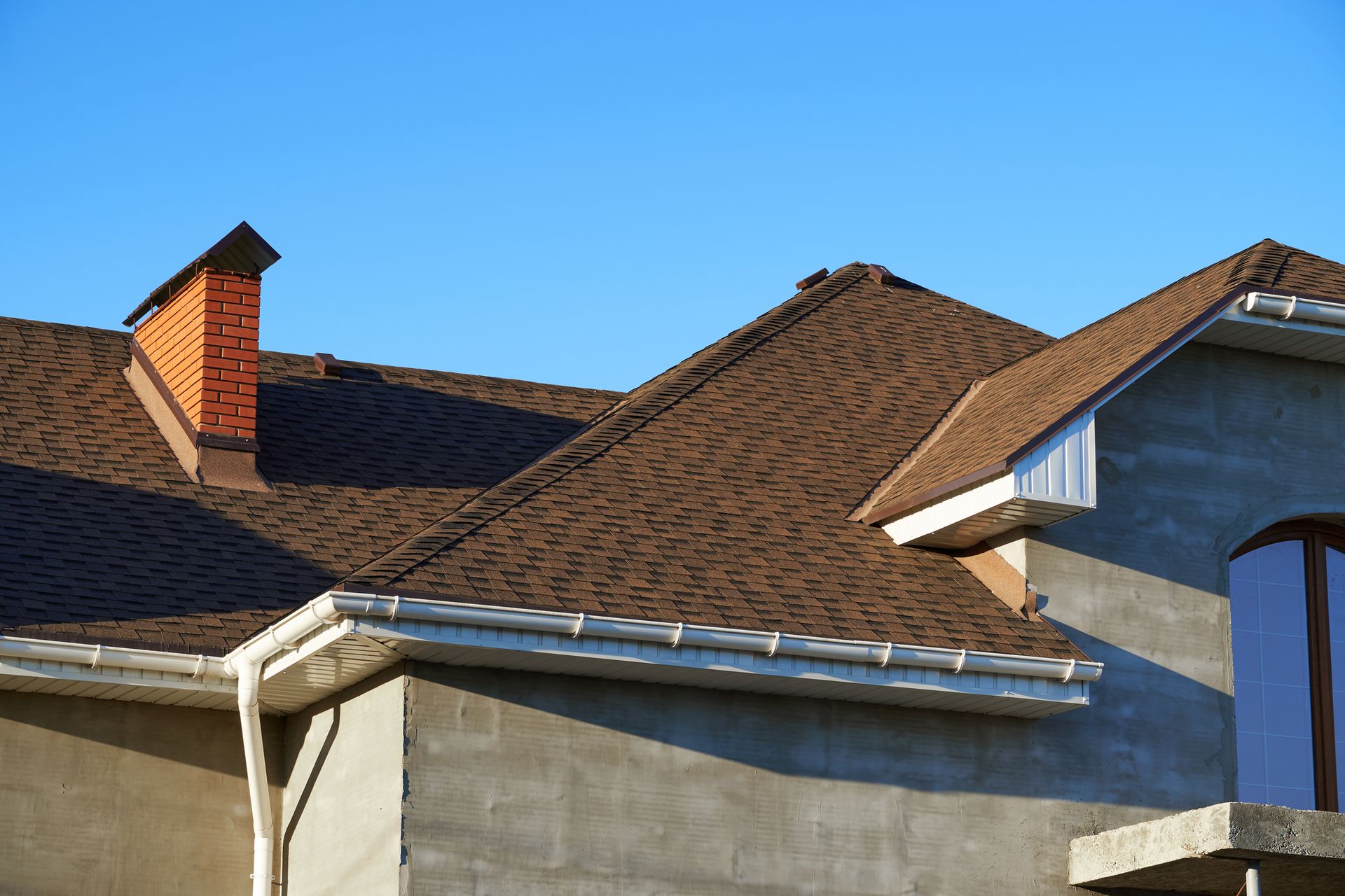 A house with a brown roof and a chimney on the roof.