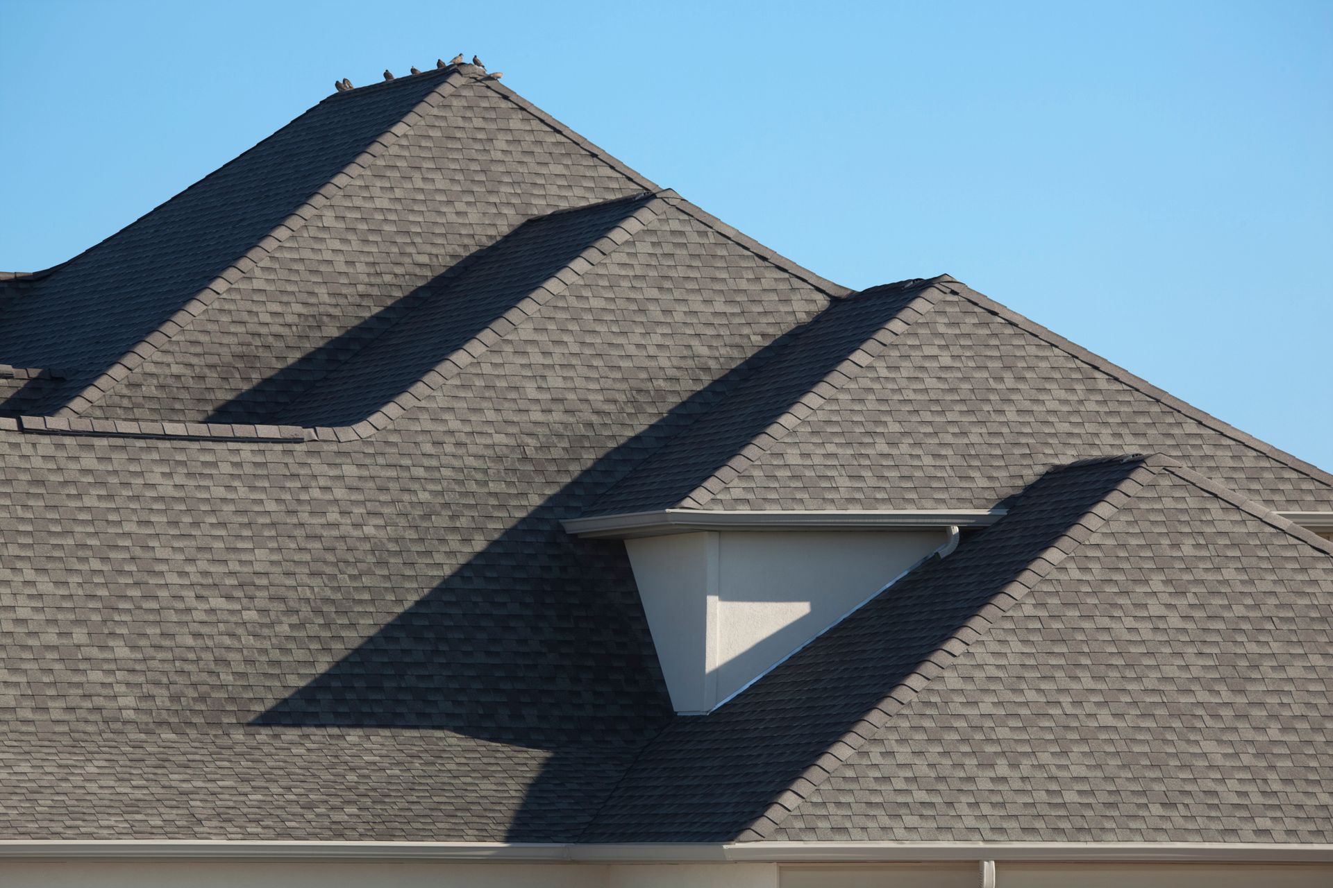 A man is standing on a ladder working on a roof. - Northfield, OH - Roofing M.R. Plank