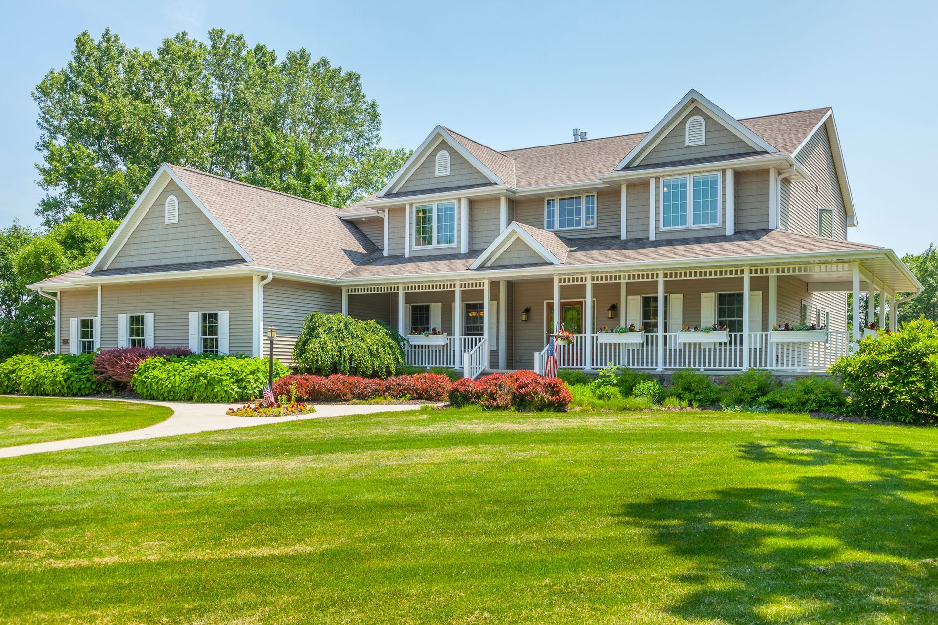 A large house with a large porch and a lush green lawn.