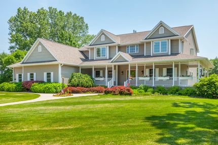 A large house with a large porch and a lush green lawn.