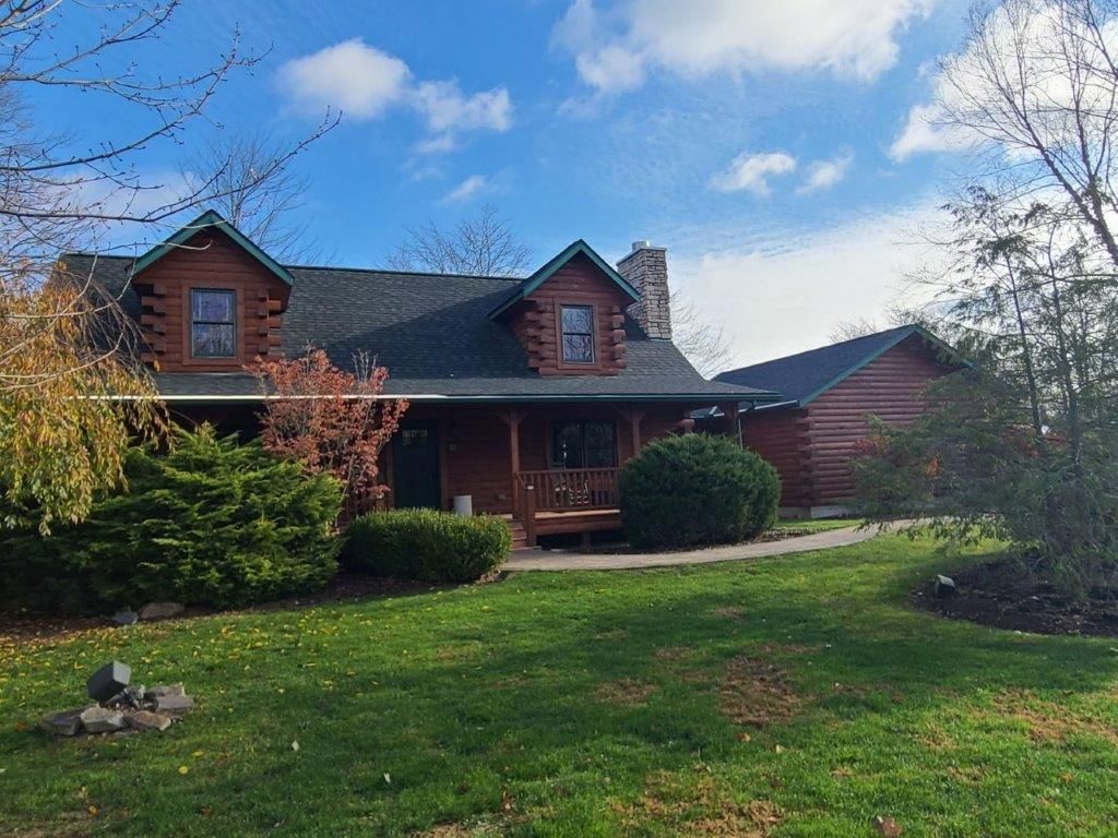 A large log cabin is sitting on top of a lush green field.