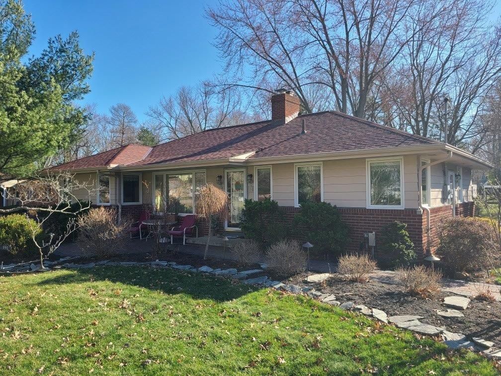 A house with a red roof and a large lawn in front of it