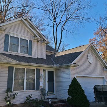 A white house with a gray roof and black shutters.