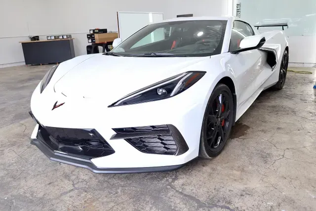 A white sports car is parked in a garage.