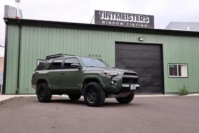 A green suv is parked in front of a green building.