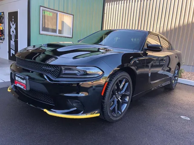 A black dodge charger is parked in front of a building.
