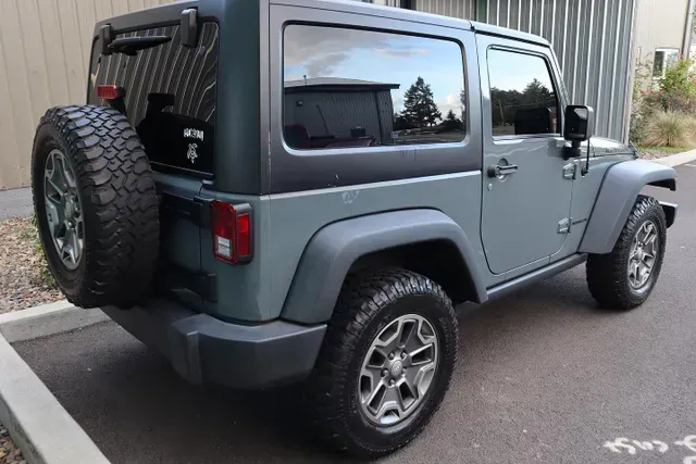 A jeep wrangler is parked in a parking lot next to a building.