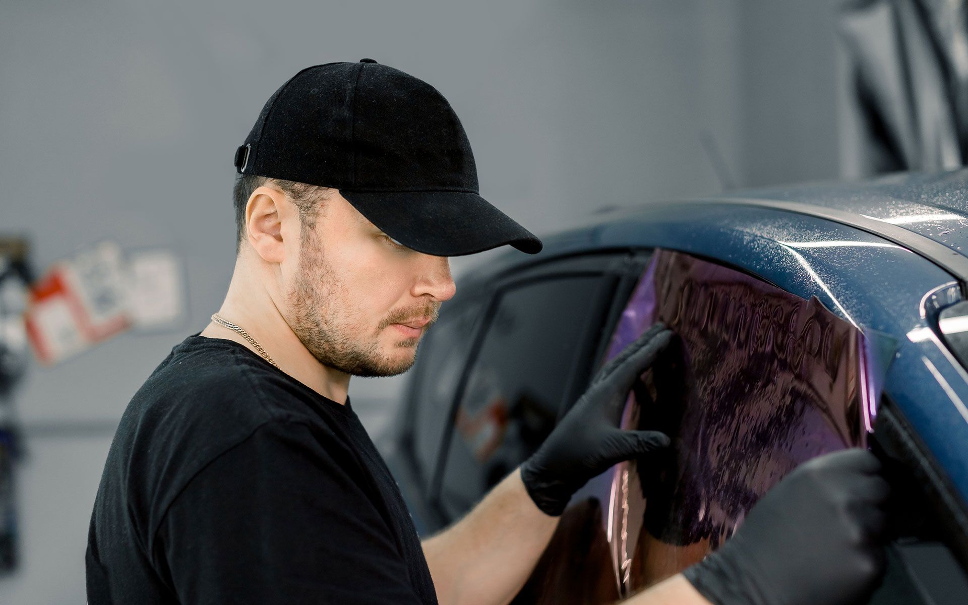 A man is applying tinted glass to a car window.