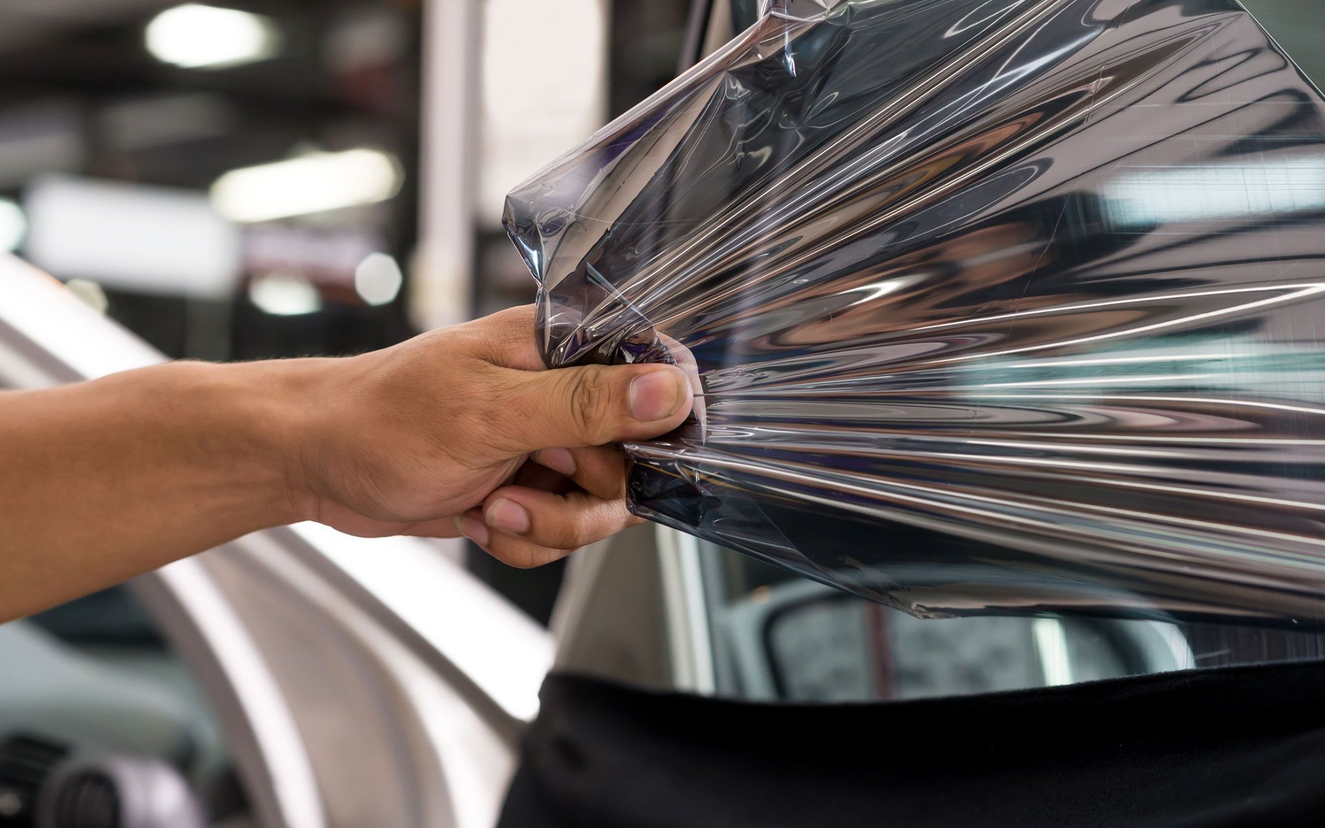 A person is applying tinted glass to a car window.