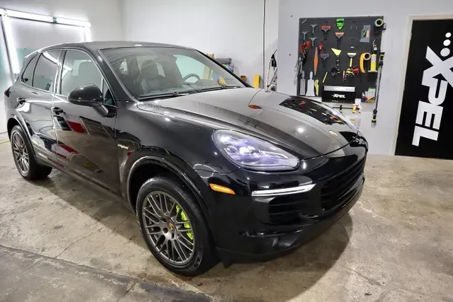 A black porsche cayenne is parked in a garage.