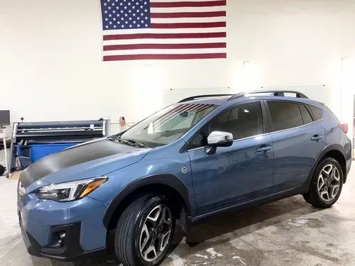 A blue subaru xv is parked in a garage in front of an american flag.