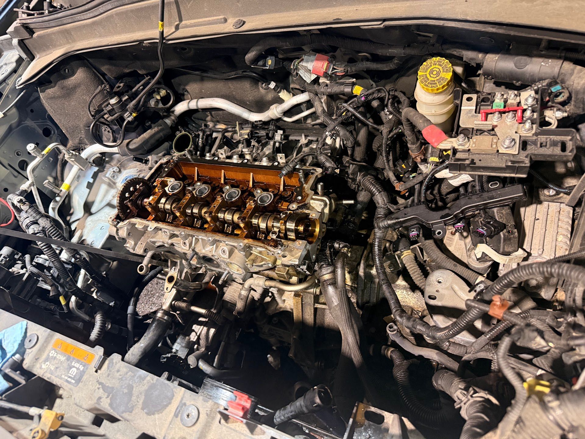 The open engine bay of a vehicle showing the exposed cylinder head and various mechanical components. | Christian's Auto Repair