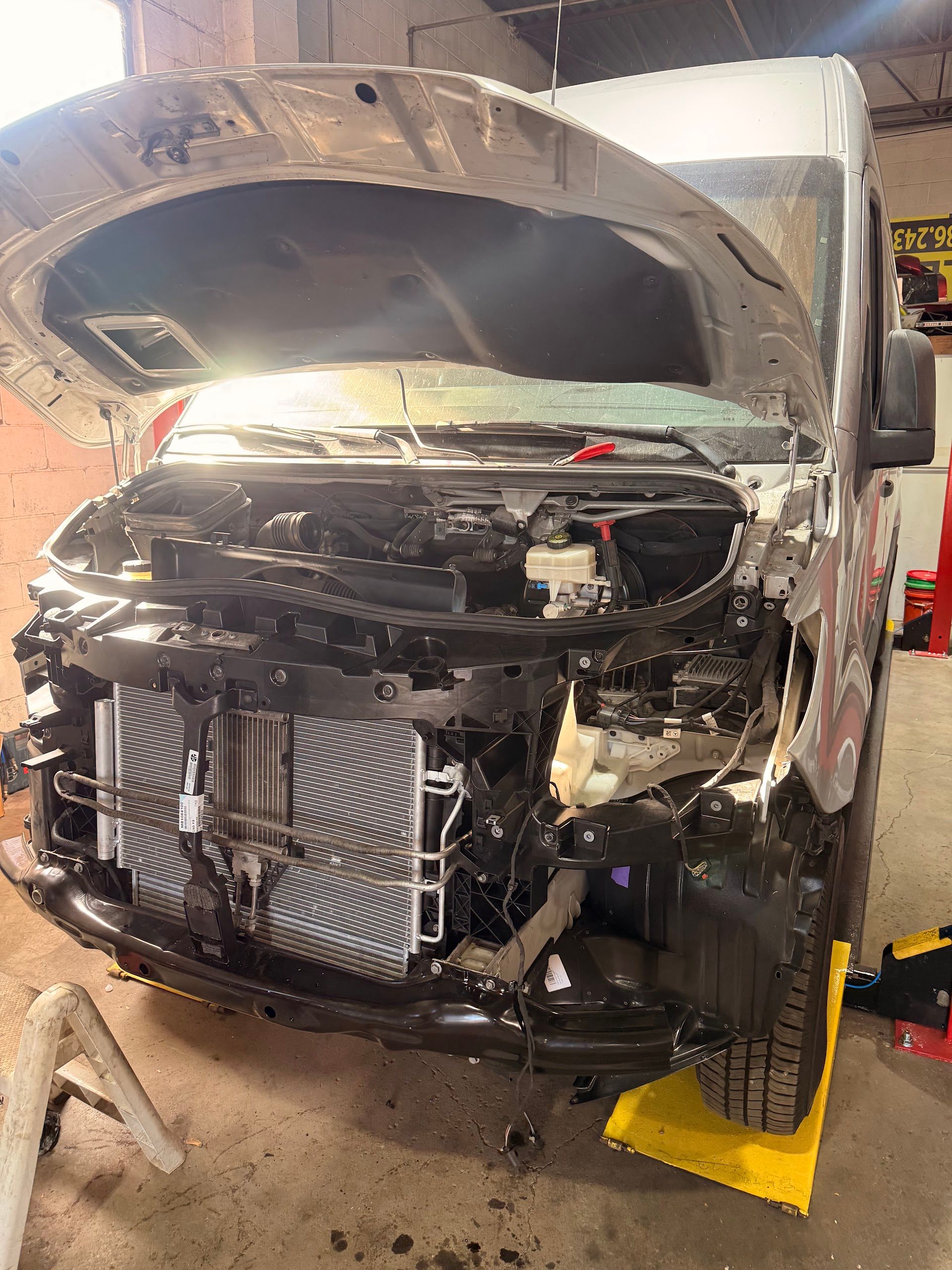 A silver van with its hood open and front bumper removed, revealing the radiator, parked inside an auto repair shop.  | Christian's Auto Repair