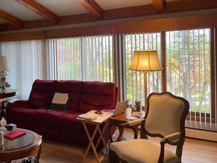 A living room with a red couch and a white chair