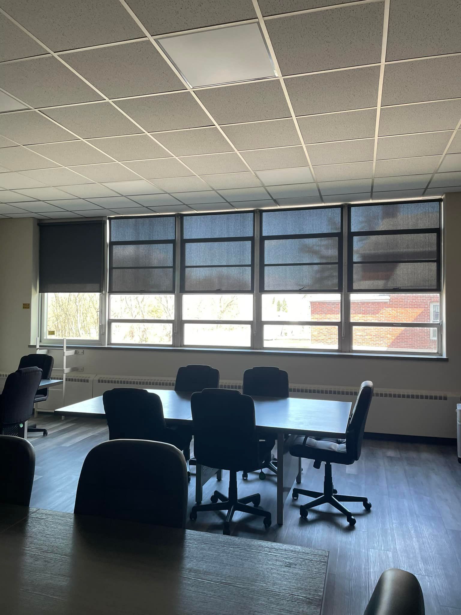 A conference room with a table and chairs and lots of windows