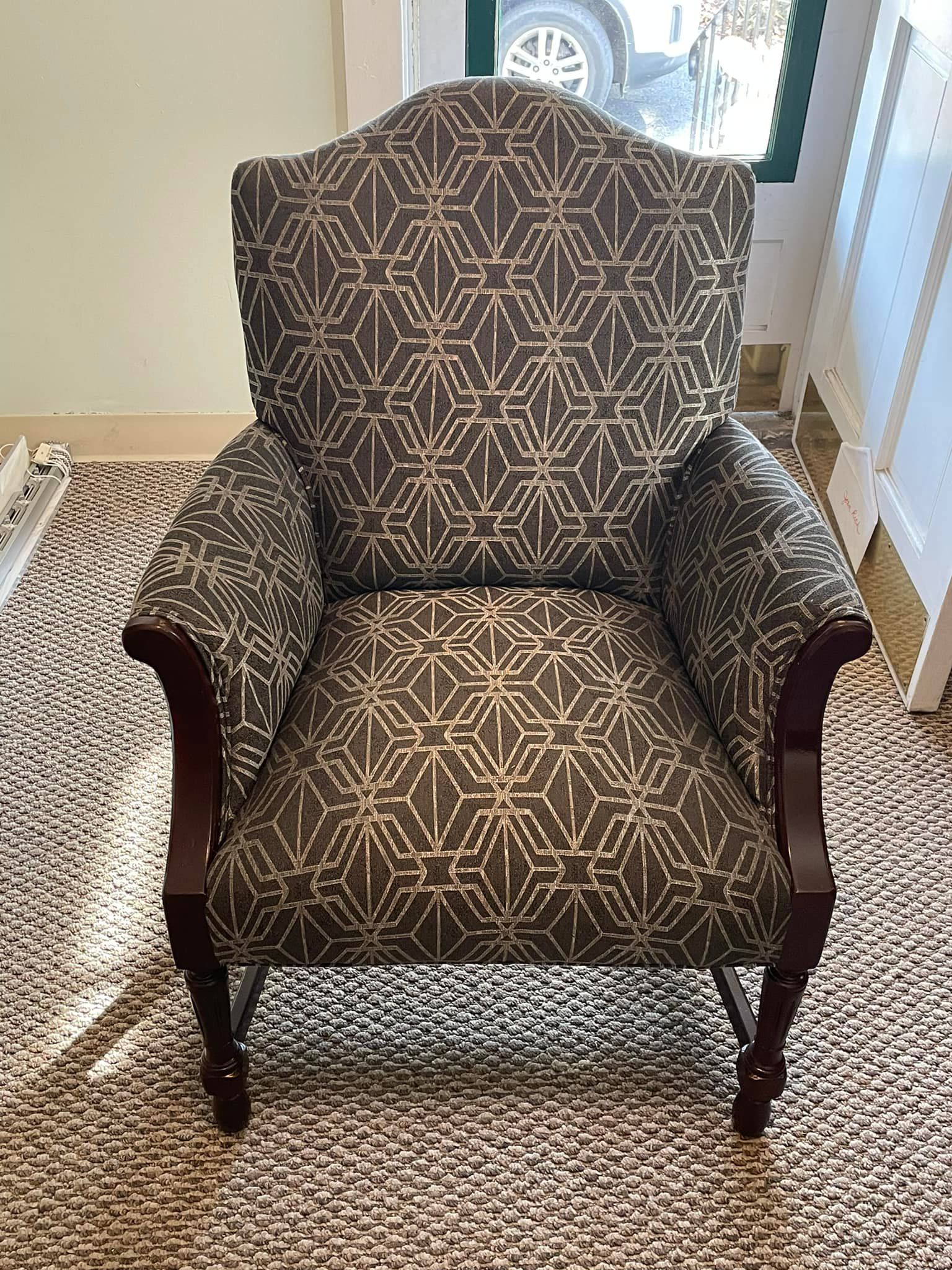 A chair with a pattern on it is sitting on a rug in a room.