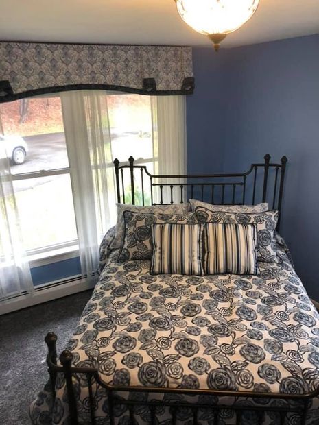 A bedroom with a bed , bench , chair and dresser. A bedroom with a bed and a window with a car parked in the background.