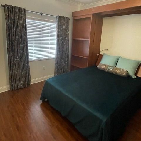 A bedroom with a bed , window and curtains.