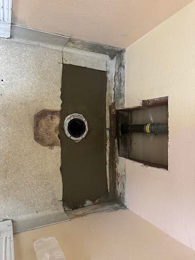 A bathroom with a hole in the wall and a hole in the floor.