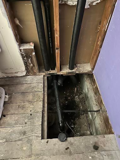 A hole in the floor with pipes coming out of it.
