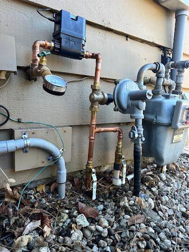 A gas meter is connected to a copper pipe on the side of a building.