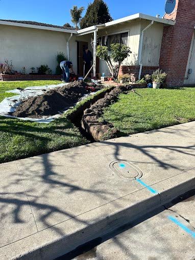 A man is digging a hole in the ground in front of a house.
