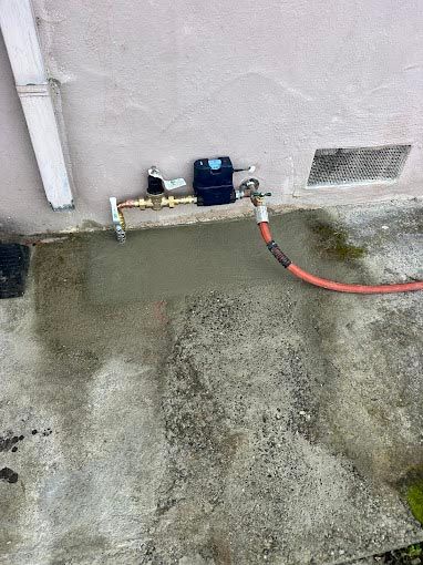 A hose is connected to a valve on the side of a building.