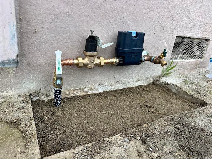 A water meter is attached to the side of a building.