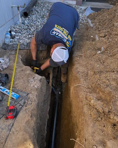 A man is working on a pipe in a trench.