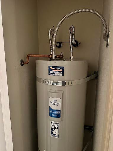 A water heater is sitting in a closet next to a door.