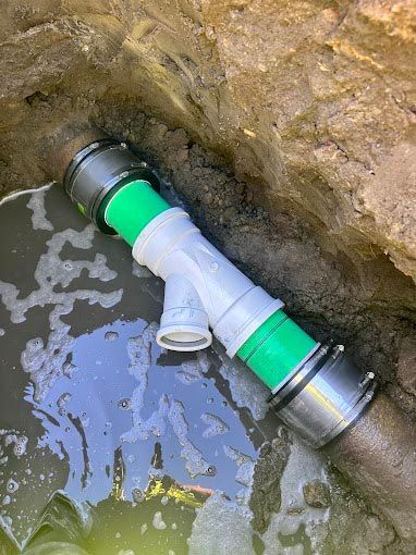 A green and white pipe is sitting in a hole in the ground.