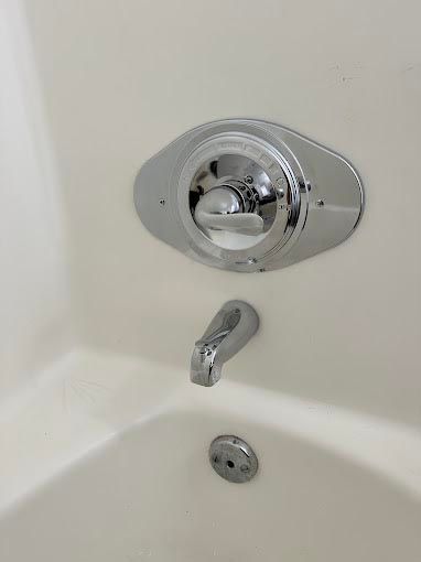 A close up of a bathtub with a chrome faucet.