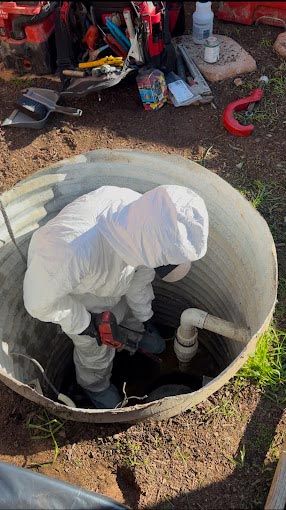 A man in a protective suit is working on a septic tank.