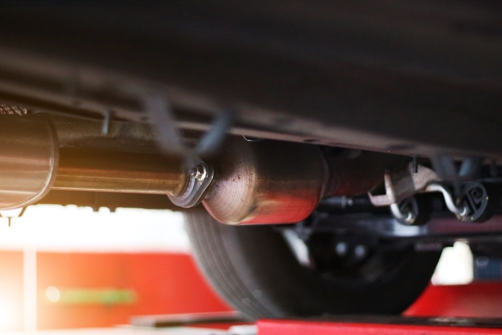 A mechanic in blue overalls holds a wrench near a white truck with its hood open for repairs.