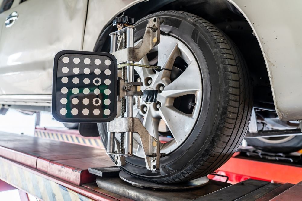 A vehicle wheel mounted on a service lift with an alignment sensor target attached to the rim in an auto repair shop.