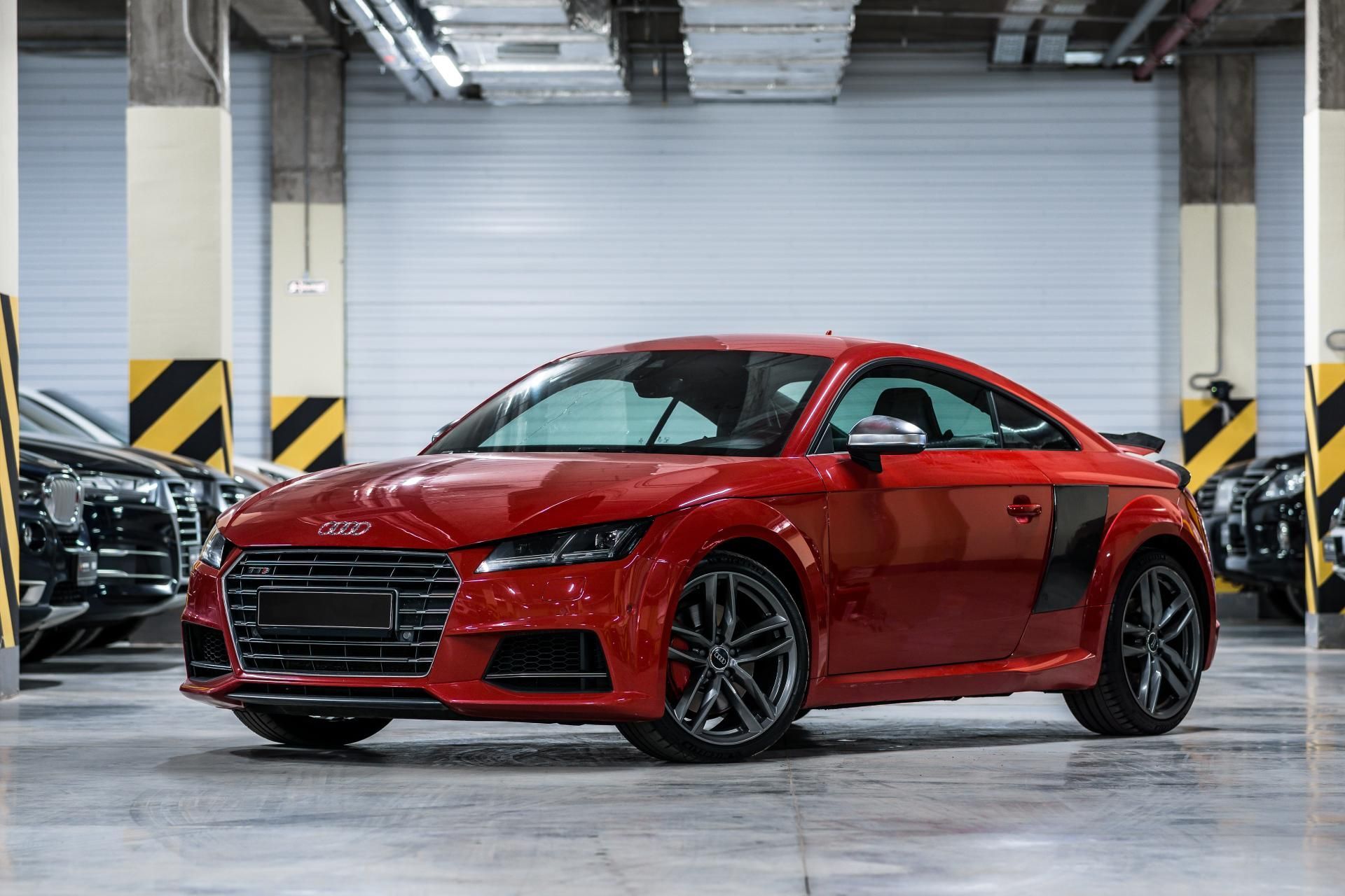 A line of semi-trucks parked on an asphalt lot under a blue, cloudy sky.