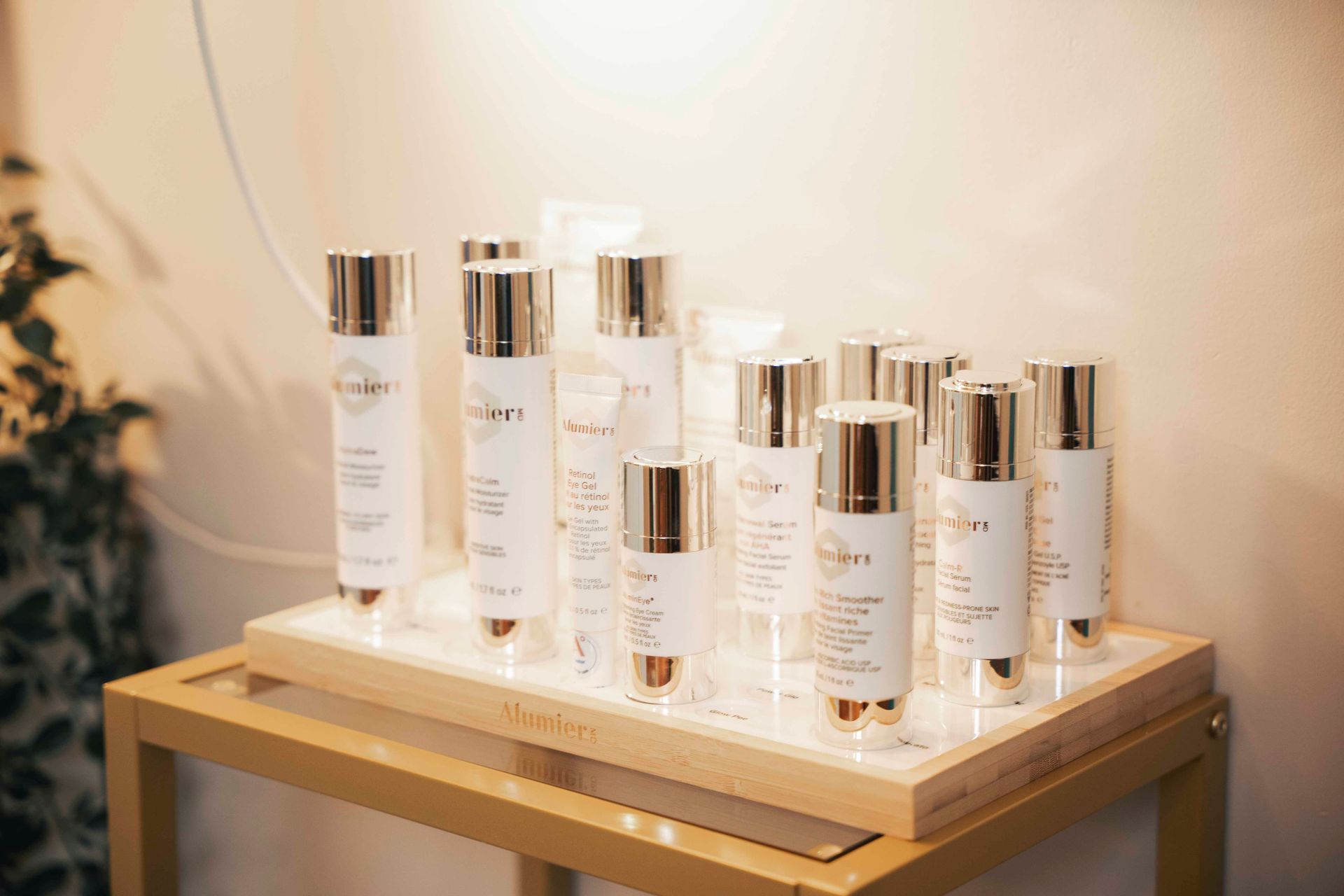 Skincare products in white and gold bottles displayed on a shelf, indoors.